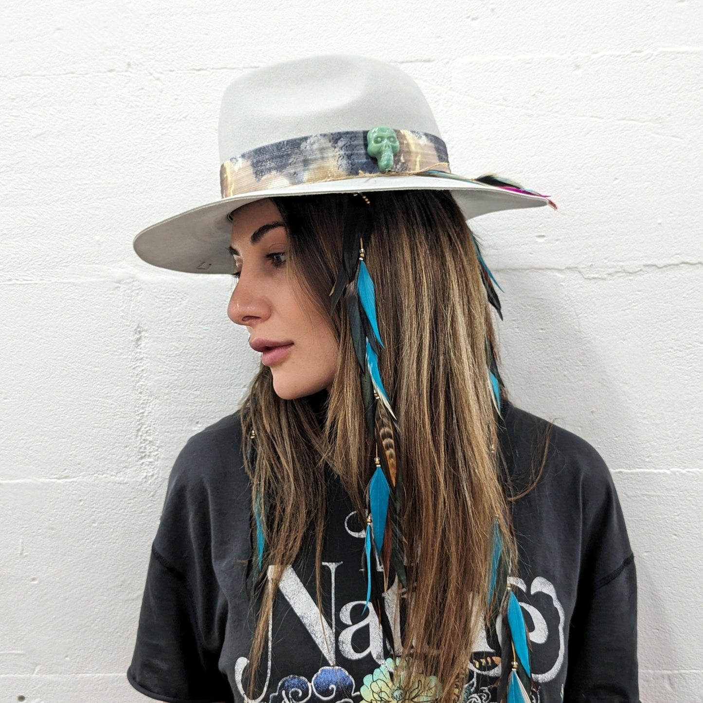 model wearing a blue hat and feather in her hair 